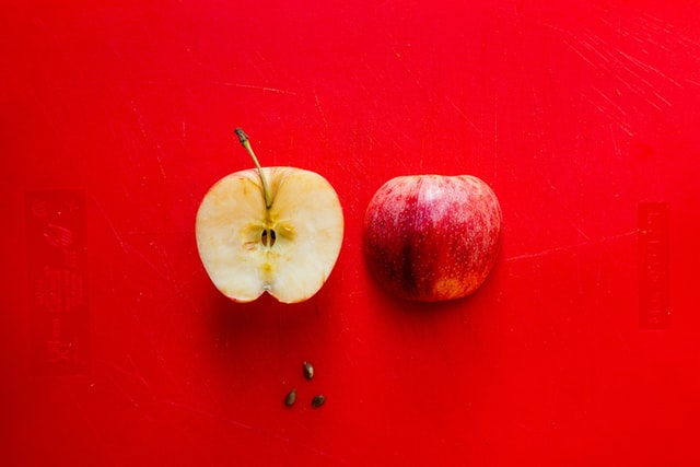 Dos mitades de una manzana roja, a la derecha se ve la cascara, a la izquierda se ve la parte de adentro de la manzana.  Foto de Louis Hansel.